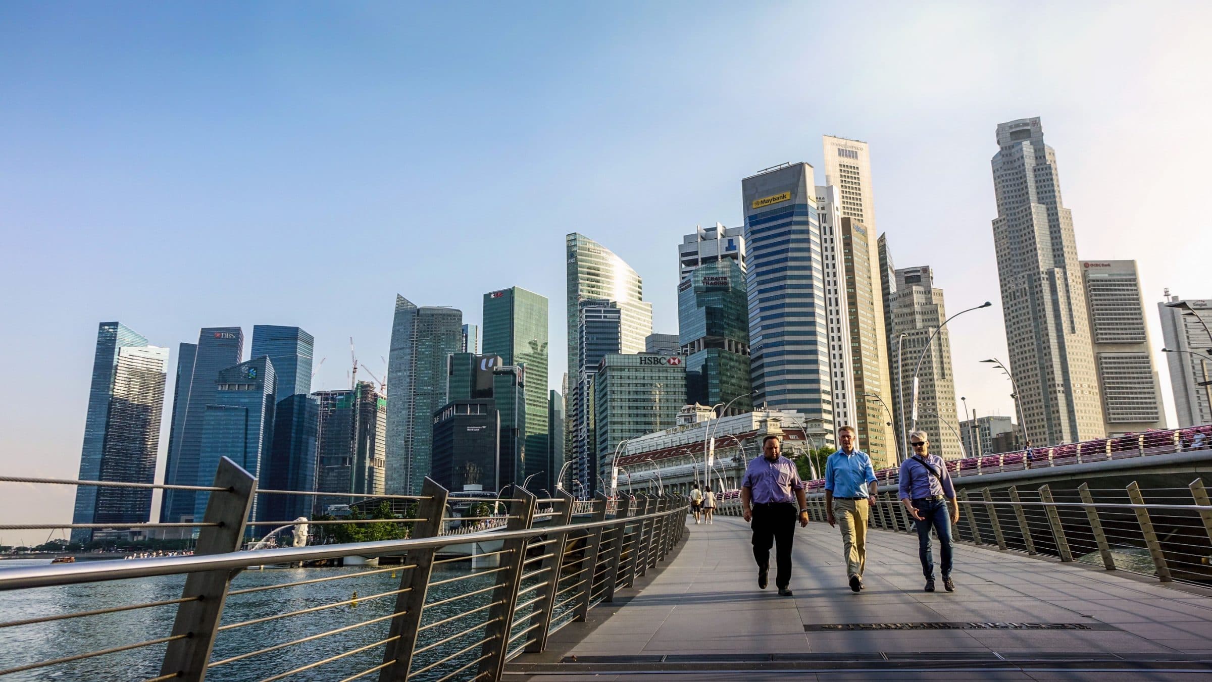 Singapore skyline at dusk with business professionals walking, representing global operations